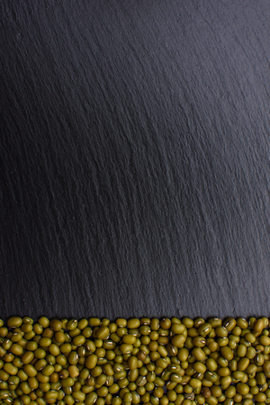 Green mash lies on a black stone board background, space for text, beans.の写真素材