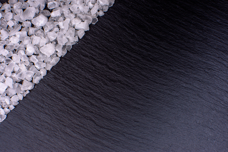 Salt, table salt lies on a black stone black board in the form of a frame, space for text.の写真素材