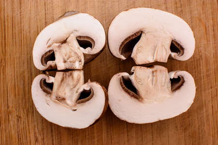 Gray mushrooms champignons lie on a wooden kitchen board.の写真素材