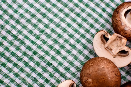 White mushrooms champignons lie on a green towel, place for text, background.の写真素材