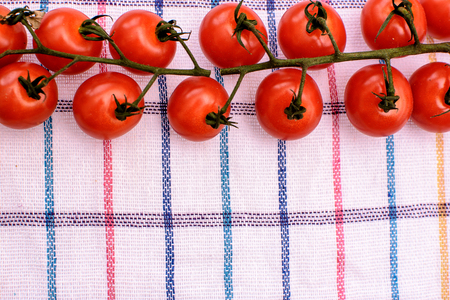 Red cherry tomatoes lie on a plaid towel, place for text.の写真素材