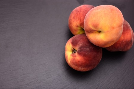 Peaches lie on a black stone slate, place for text.の写真素材