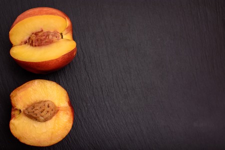 Peaches lie on a black stone slate, place for text.の写真素材