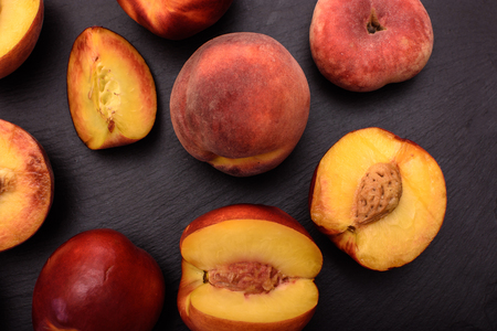 Peaches lie on a black stone slate, place for text.の写真素材