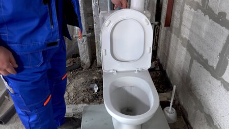 Plumber checks the operation of the toilet, drains the water in the toilet.の写真素材