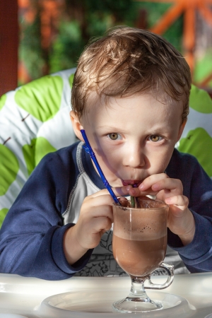 Kid drinking a chocolate Cocktail in summer restaurantの写真素材
