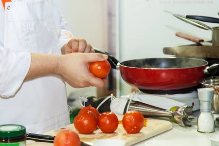 Chef prepares tomatoes for vegetarian mealsの写真素材