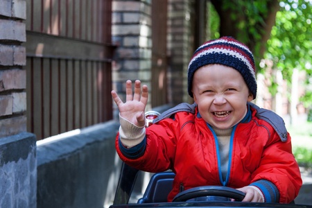 Smiling boy at the wheel toy electromobile