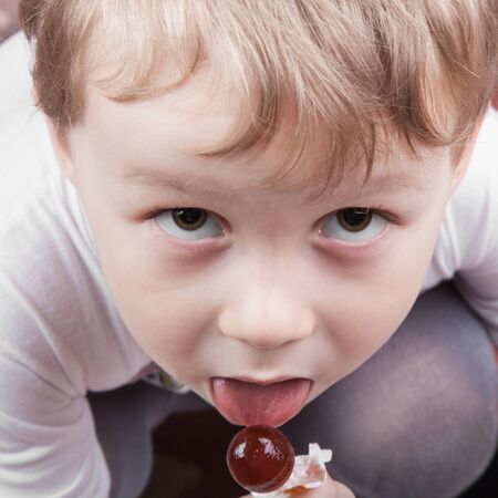 Portrait of kid licking a lollipop close up