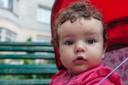 Portrait of baby girl sitting in stroller outdoors, closeupの写真素材