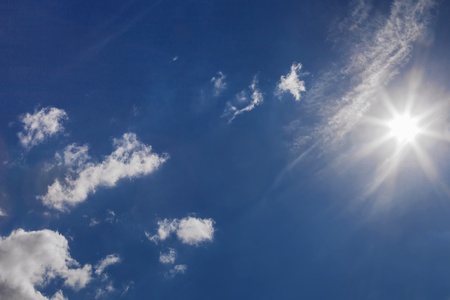 Bright sun in the blue sky with white cloudsの写真素材
