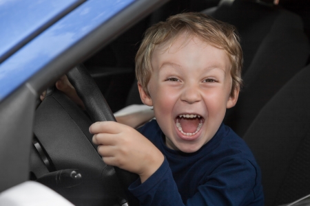 Young boy is happy behind wheel of carの写真素材