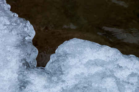 The ice edge is covered with snow on the background of the current water