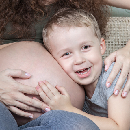 Boy listening belly of his pregnant momの写真素材
