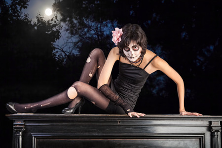 Young woman with make-up for Halloween against a night landscape with a full moonの写真素材