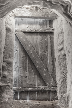 Old wooden door from basement is covered with hoarfrostの写真素材