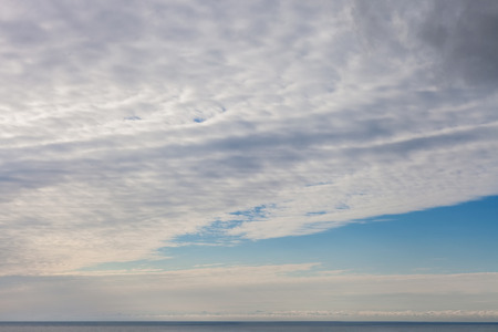 White clouds in blue sky above sea surfaceの写真素材