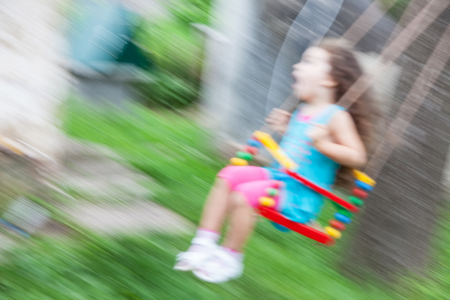 Little girl on swing with motion blure, blurred photoの写真素材
