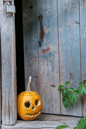Halloween pumpkin (Jack o lantern) on the background of an old wooden door , ready for text invitation or card for halloween partyの写真素材