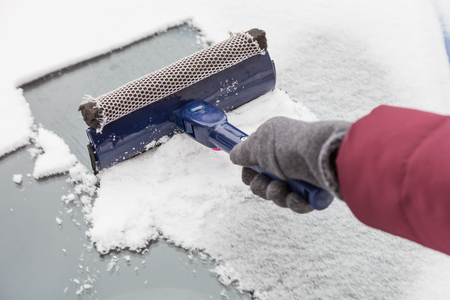 Cleaning the windshield of the car from snow and ice with scraper in winterの写真素材