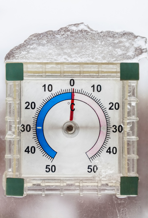 Photo of thermometer outside the window in winter during thaw closeup