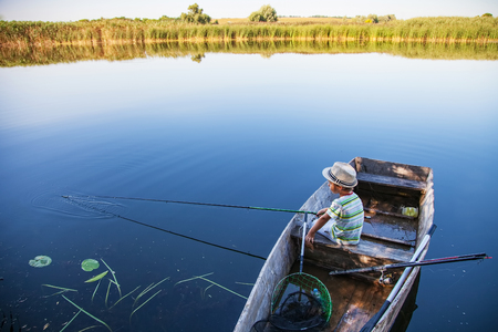 Young fisherman catches fish from boat on a fishing tackleの写真素材