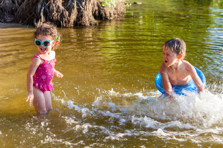 Children splash water on the beach, boy and girl have fun playing in summerの写真素材