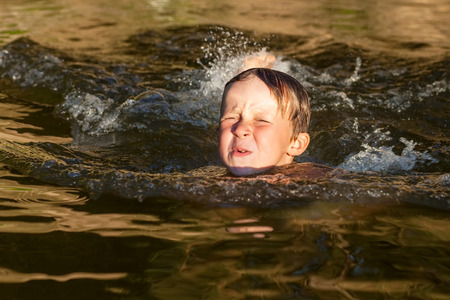 Little boy is swimming on the river with sunlightの写真素材