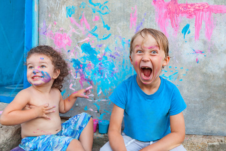 Boy and a girl are playing with paints for face and body outdoorsの写真素材