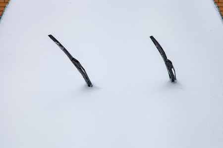 Car windshield covered with snow, wipers stick outの写真素材