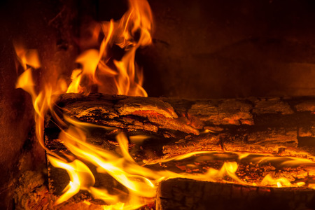 Burning firewood in the fireplace closeup, texture of fire and flame
