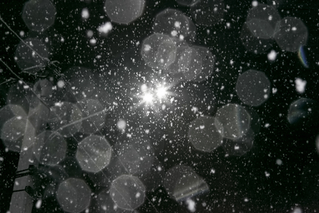 Electric lantern on pole at night during snowfalll against the black sky