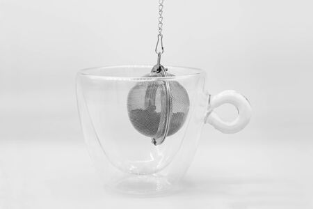 Tea strainer with tea leaves in glass empty cup, close-up on a white backgroundの写真素材