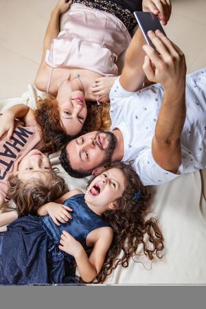 Happy family taking selfie picture with smartphone at home, mother, father, son and daughter, holidays, technology and people conceptの写真素材