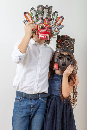 Girl and boy posing in Indian Mayan Aztec wooden mask