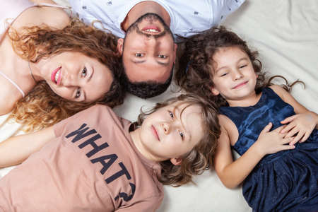 Father lies in the middle between son and daughter, family portrait