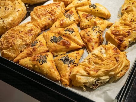 Golden brown baked puff pastry buns, filled , sprinkled with sesame seeds, on baking tray, homemade...