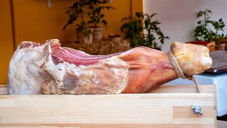 Slicing jamon mounted on a hamoner, Jamon serrano dish of spanish national cuisine. Hamon pork leg on stand in the marketplaceの写真素材