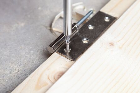 Install door hinges on a wooden door, screwing in the screwの写真素材