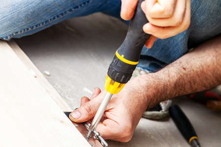 Screwing a door hinge to a wooden door frame with screwdriver