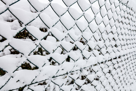 Chain link fence with snow background in winter close upの写真素材
