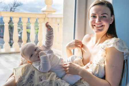 A mother plays with a child sitting on the floor by the windowの写真素材