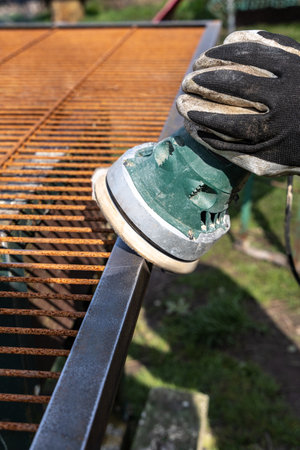 Grinding a new rusty metal grate with a vibrating sanderの写真素材