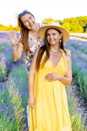 Two women pose in a blooming lavender field in summerの写真素材