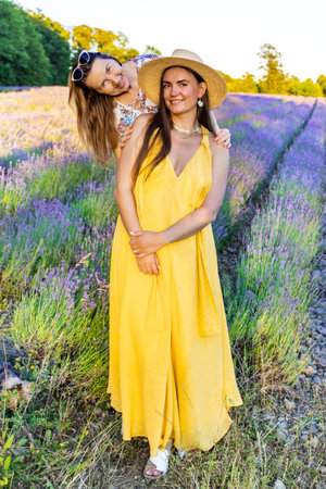 Two women pose in a blooming lavender field in summerの写真素材