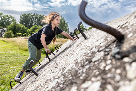 A girl climbs a concrete wall, a climbing wall outdoorsの写真素材