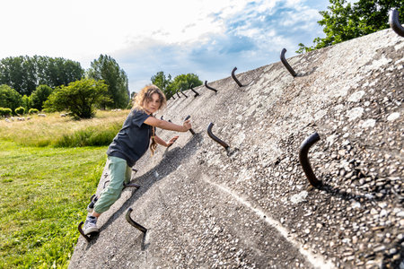 A girl climbs a concrete wall, a climbing wall outdoorsの写真素材