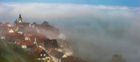An ancient European town is shrouded in fog in the early morning in springの写真素材