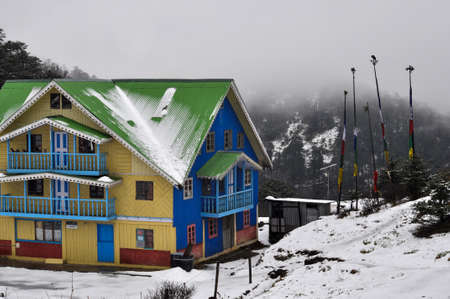 Lively looking cottage brightly coloured blue green yellow covered with snow