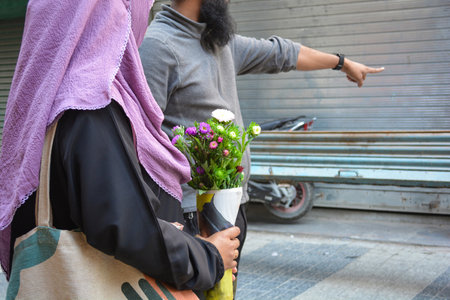 Portrait of a muslim girl holding bouquet and boy on the streetの写真素材